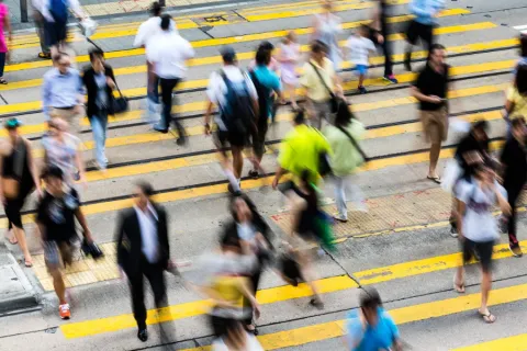 Commuters crossing a busy city street, seen from above