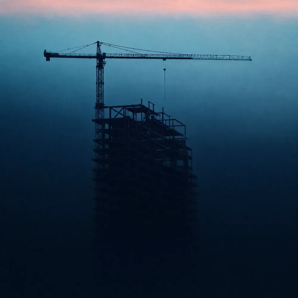 A tower crane over a building under construction at dusk